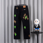 Black denim pants with green cross and tan leopard-style cross embroidery