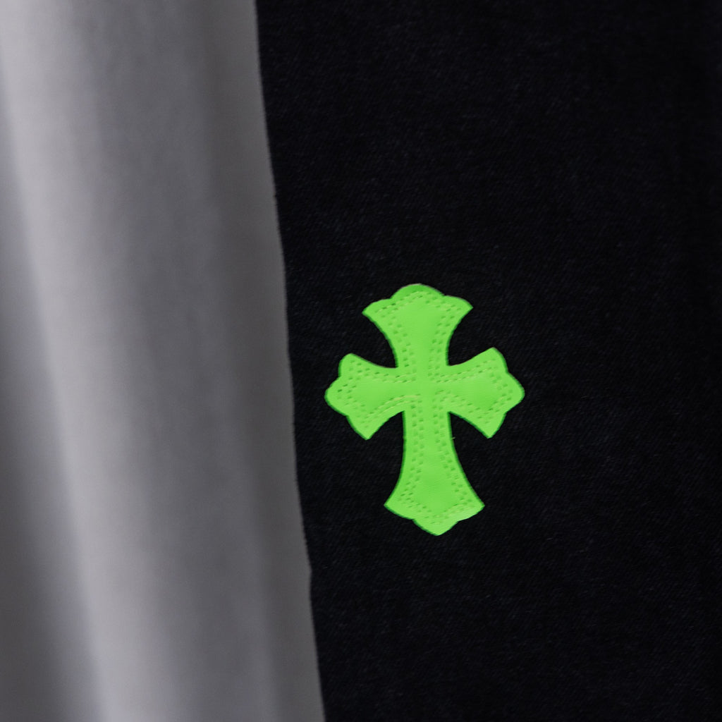 Black denim pants close-up of bright green cross embroidery detail