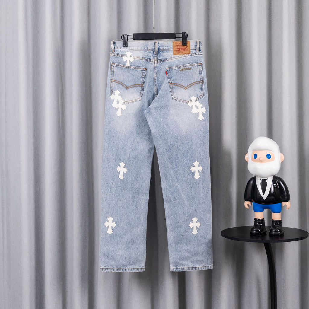 Light blue denim jeans with white cross patches, distressed wash, belt loops.