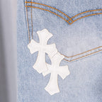 Three white cross patches on light blue denim, close-up of stitched area.