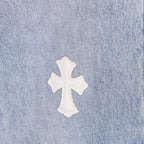 White cross applique on light blue denim, close-up of fabric texture.
