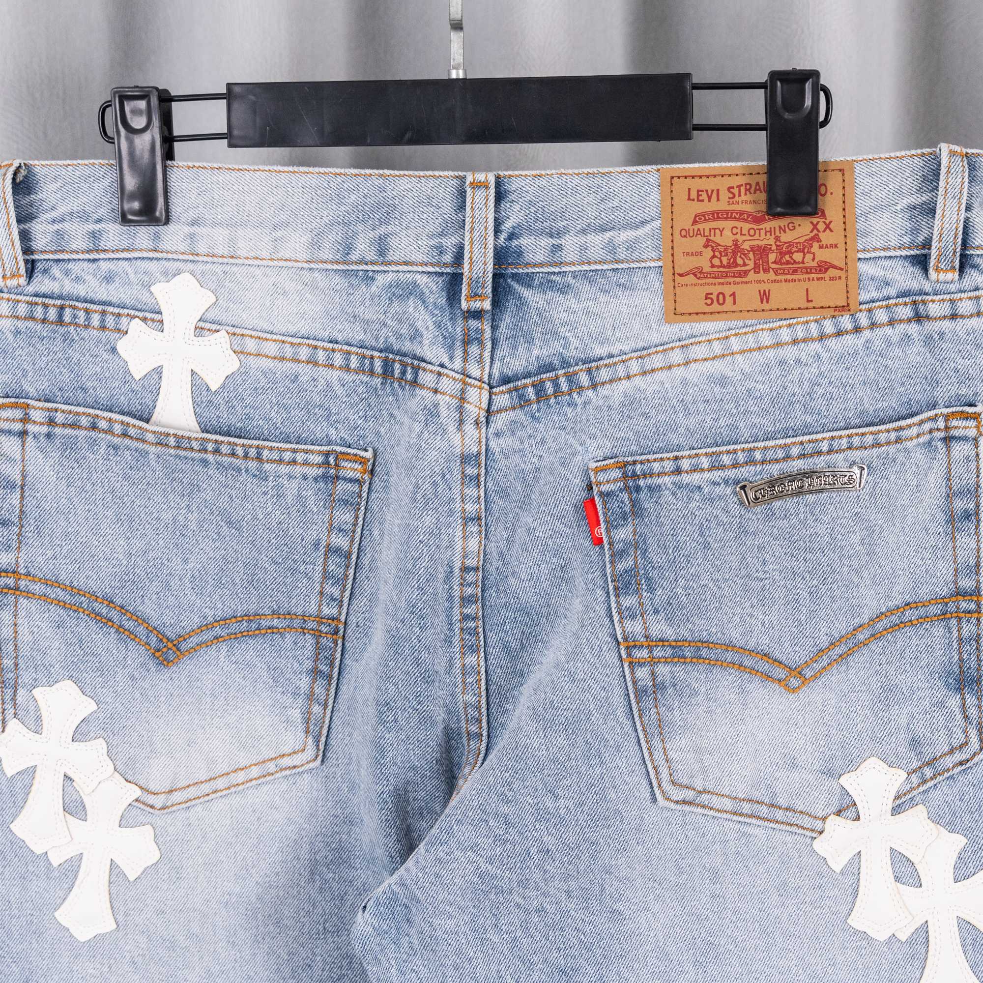 Denim jeans waist and front pockets with white cross patches, button and zip.