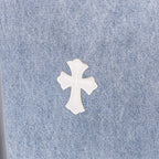White cross applique on light blue denim, close-up with visible seam texture.