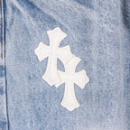 Chrome pants denim close-up with white cross applique on light blue fabric