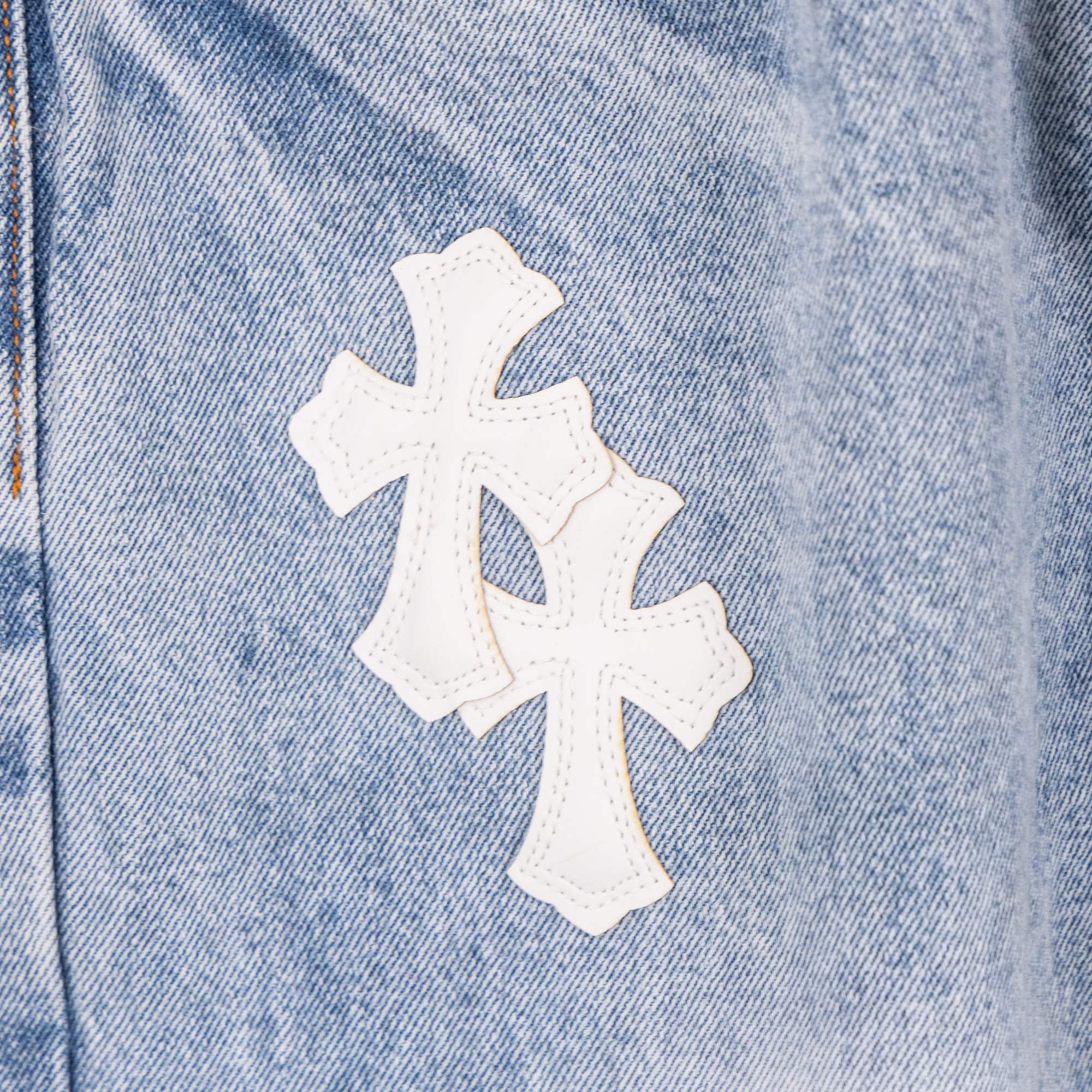 Chrome pants denim close-up with white cross applique on light blue fabric