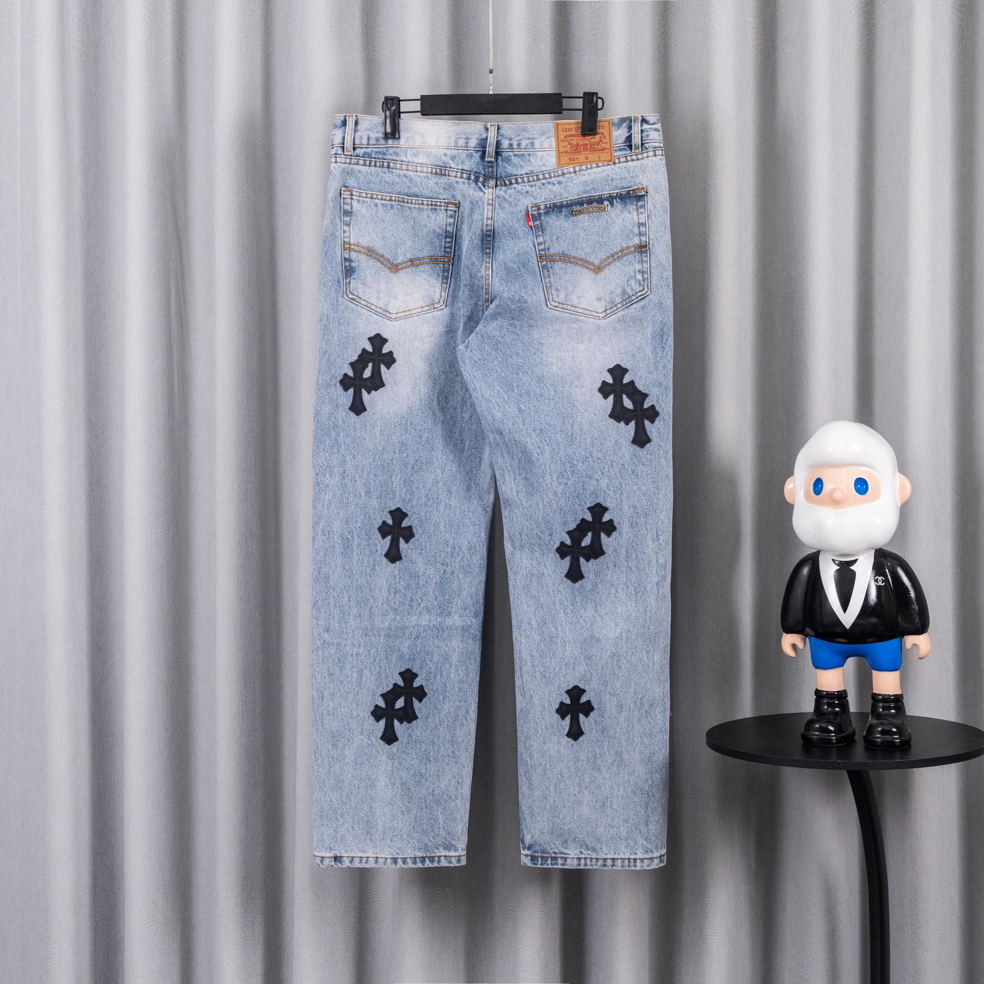 Light blue denim jeans back view with black cross patches and straight legs