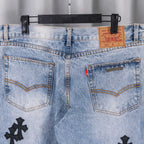 Light blue denim jeans front with two front pockets and black cross embroidery