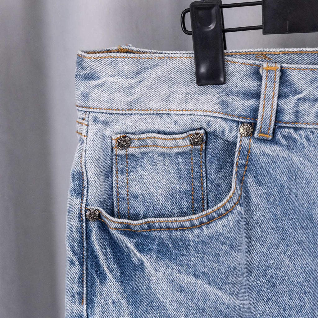 Light blue denim jeans back pocket with curved stitching and metal button