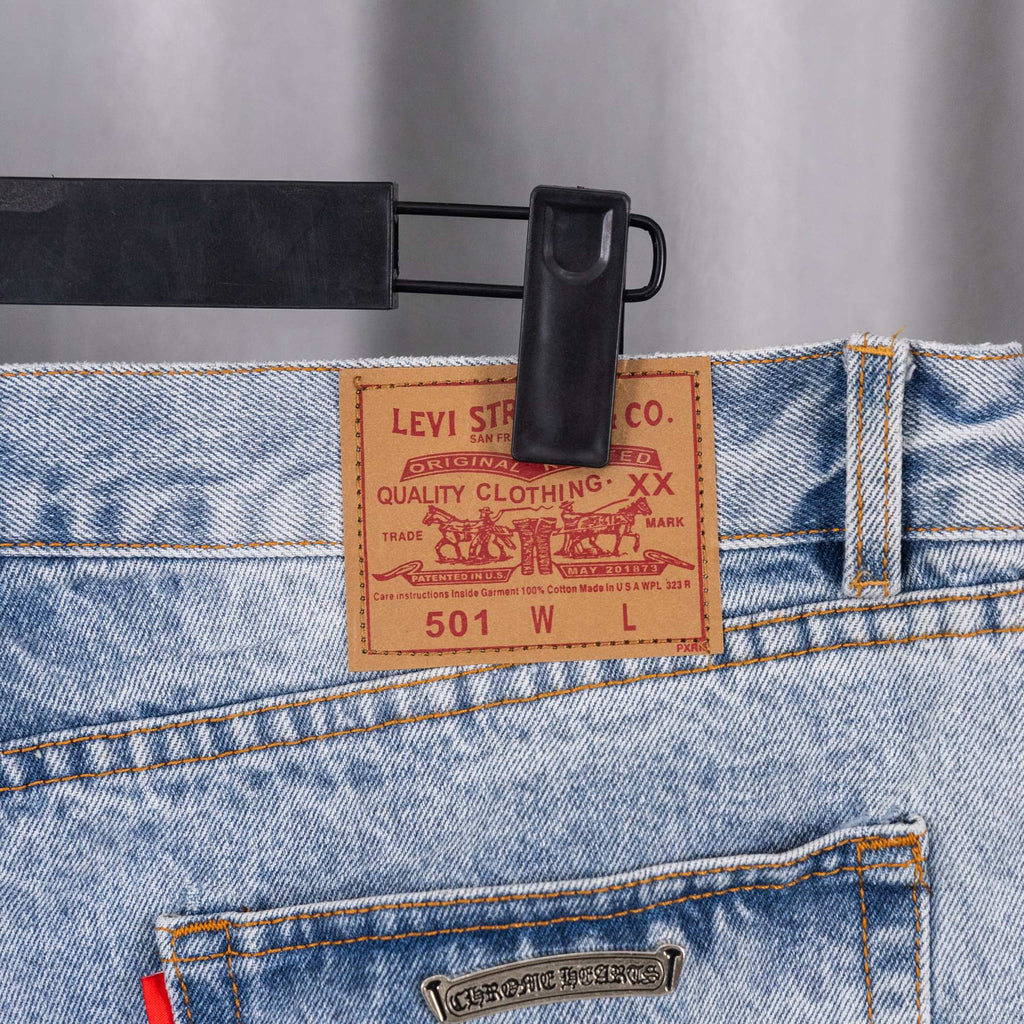 Levi-style patch on light blue denim jeans waistband with stitched orange seams