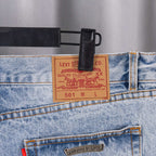 Levi-style patch on light blue denim jeans waistband with stitched orange seams