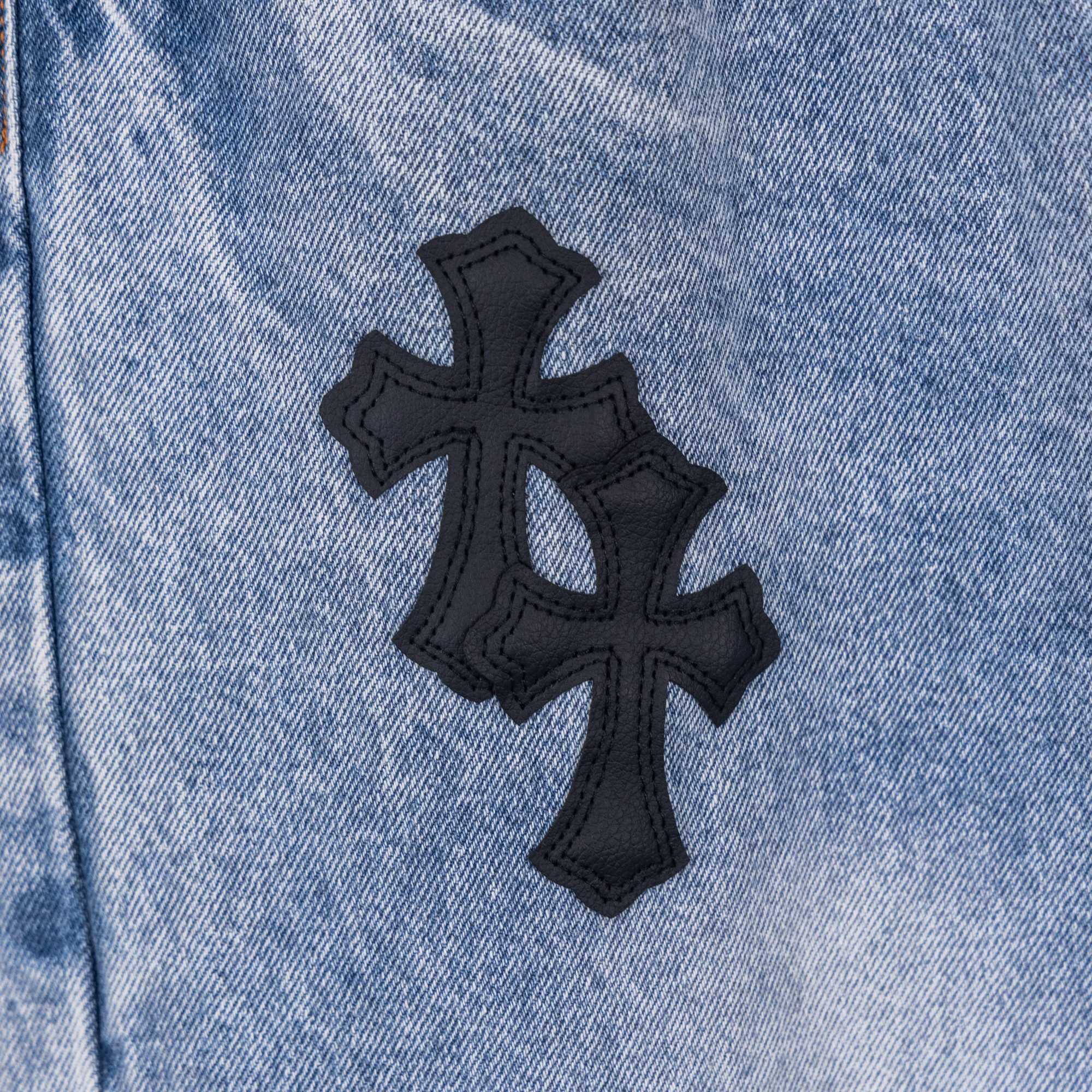 Light blue denim pants with black cross appliqué patch
