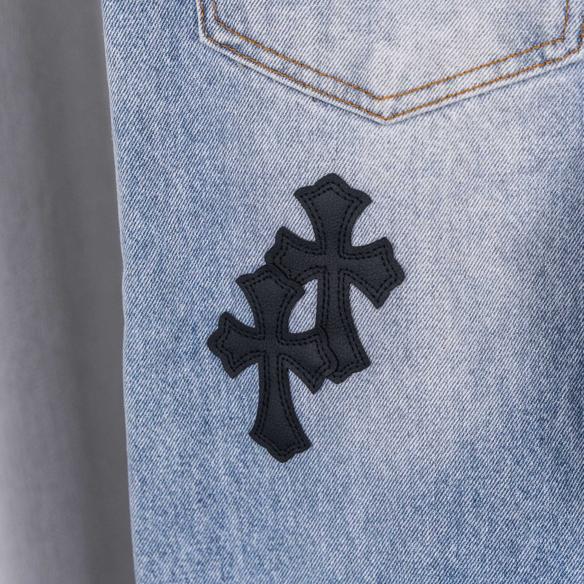 Light blue denim pants with centered black cross patch