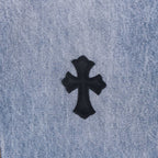 Light blue denim pants with small black cross appliqué