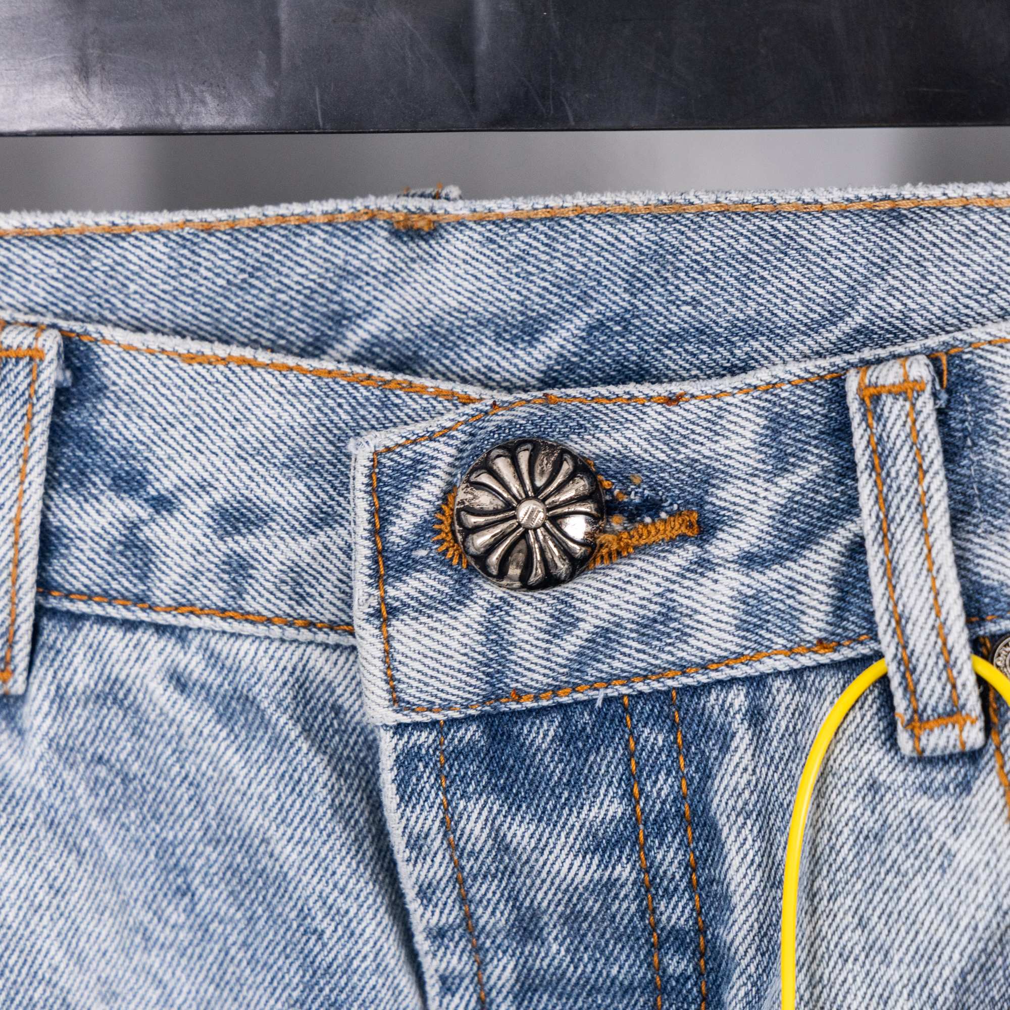 Light blue denim jeans back pocket with decorative snap and stitching