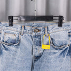 Light blue denim pants with belt loops, front fly, and yellow tag