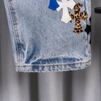 Light blue denim jeans with stitched hem and decorative cross patches