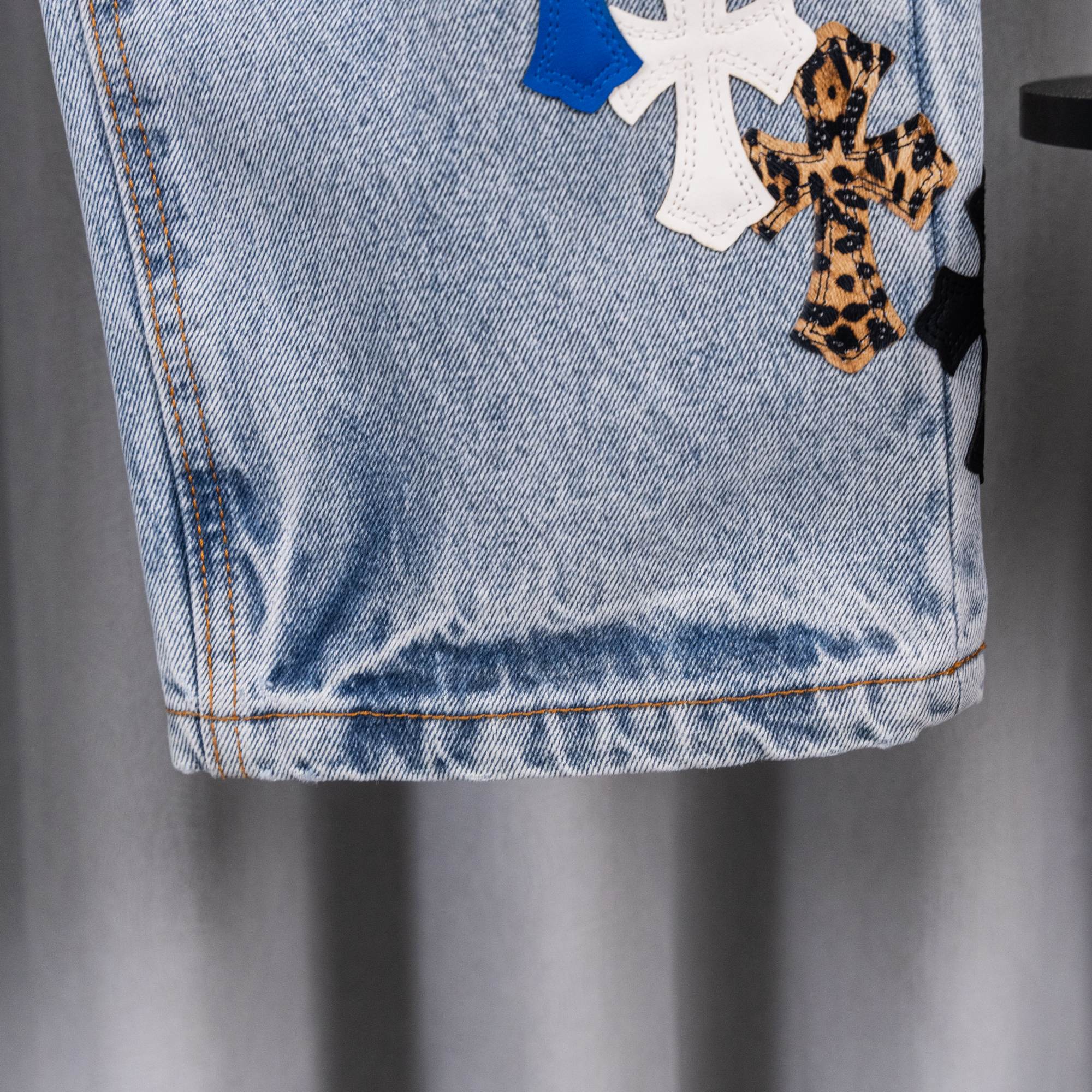 Light blue denim jeans with stitched hem and decorative cross patches