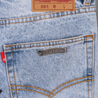 Light blue denim jeans back pocket with metal brand tag and tan topstitching