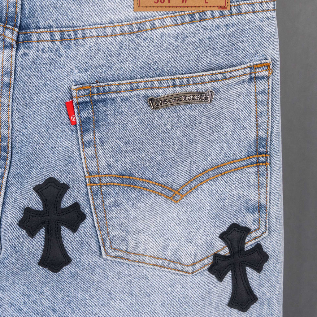 Light blue denim jeans front pocket with metal label and black cross patches