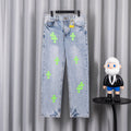 Light blue denim pants with neon green cross patches, front view on hanger