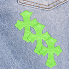 Neon green cross patch appliques on light blue denim fabric
