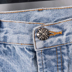 Light blue denim jeans pocket close-up with metal button and orange stitching