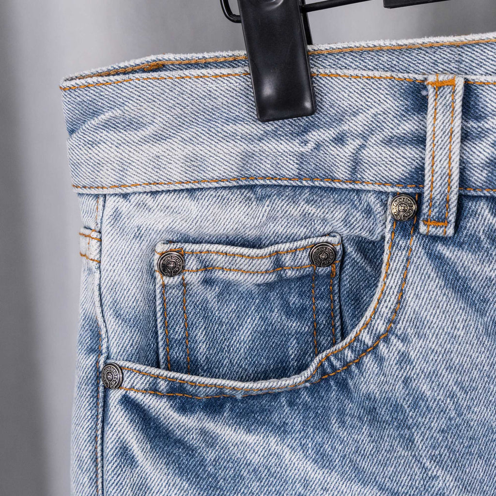 Light blue denim pants front pocket and belt loop close-up with metal buttons
