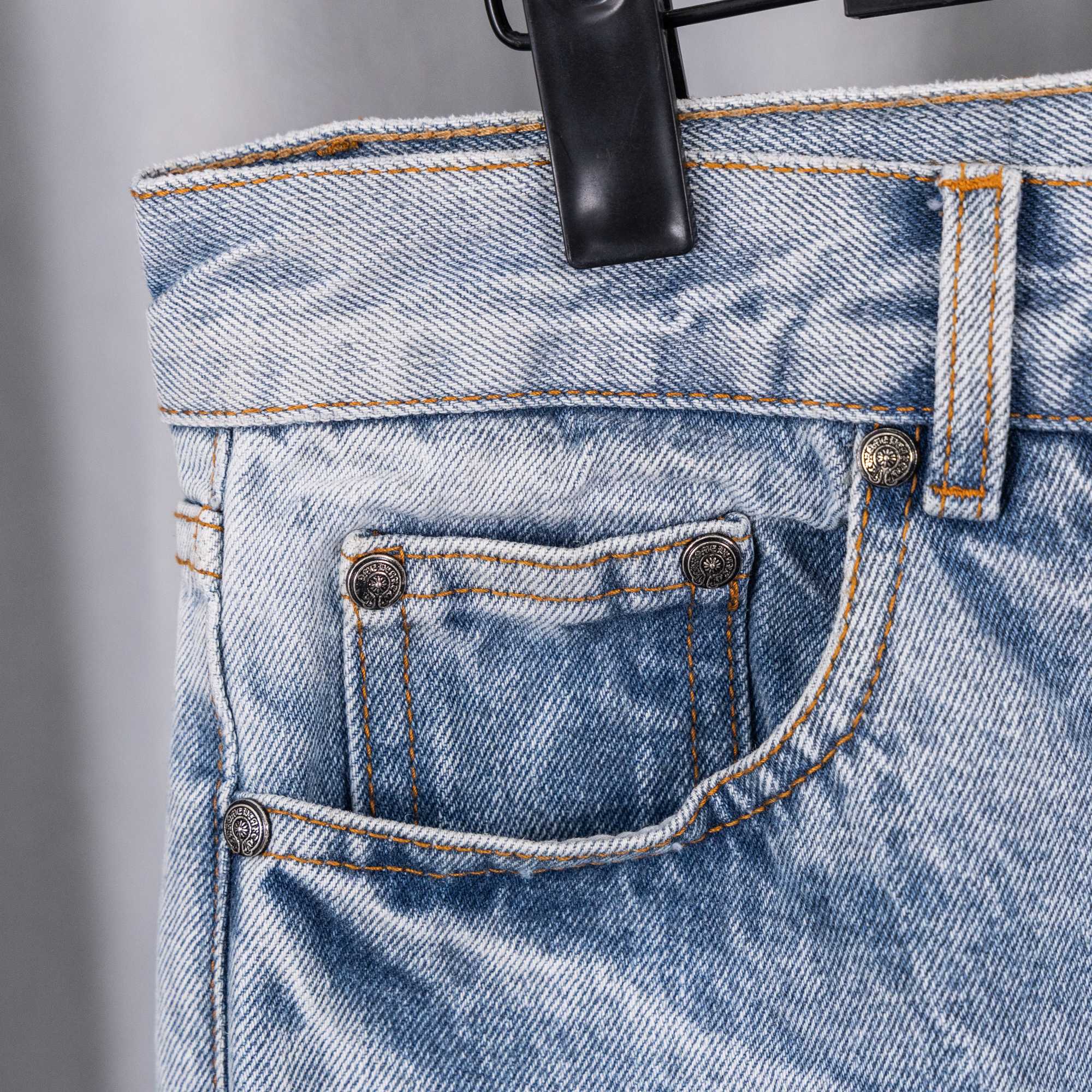 Light blue denim pants front pocket and belt loop close-up with metal buttons