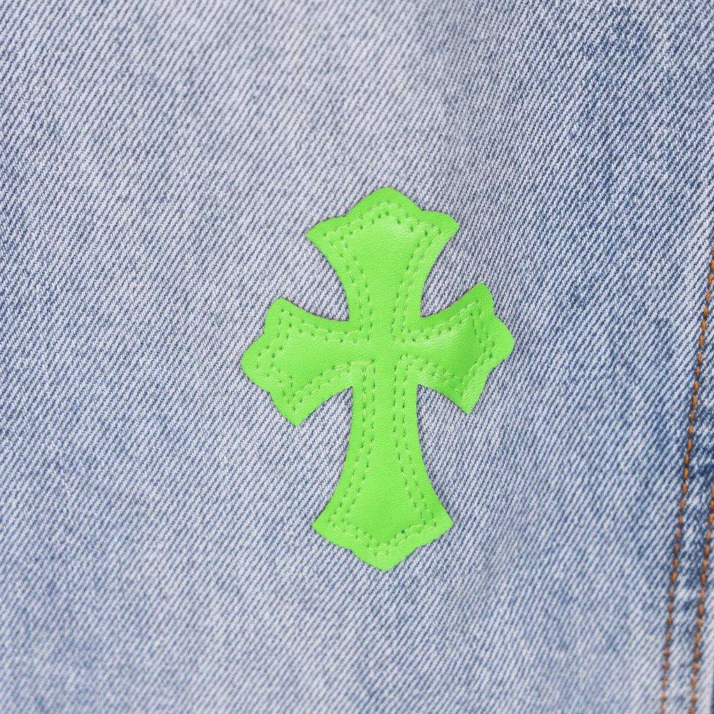 Neon green cross patch on light blue denim near seam