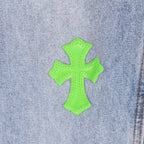 Neon green cross patch on light blue denim near seam
