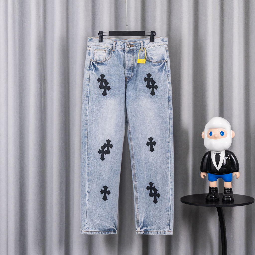 Light wash denim pants with black cross patches on front and back