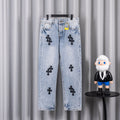 Light wash denim pants with black cross patches on front and back