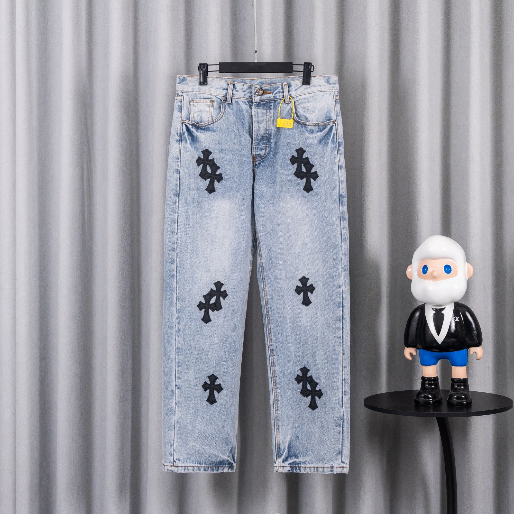 Light wash denim pants with black cross patches on front and back