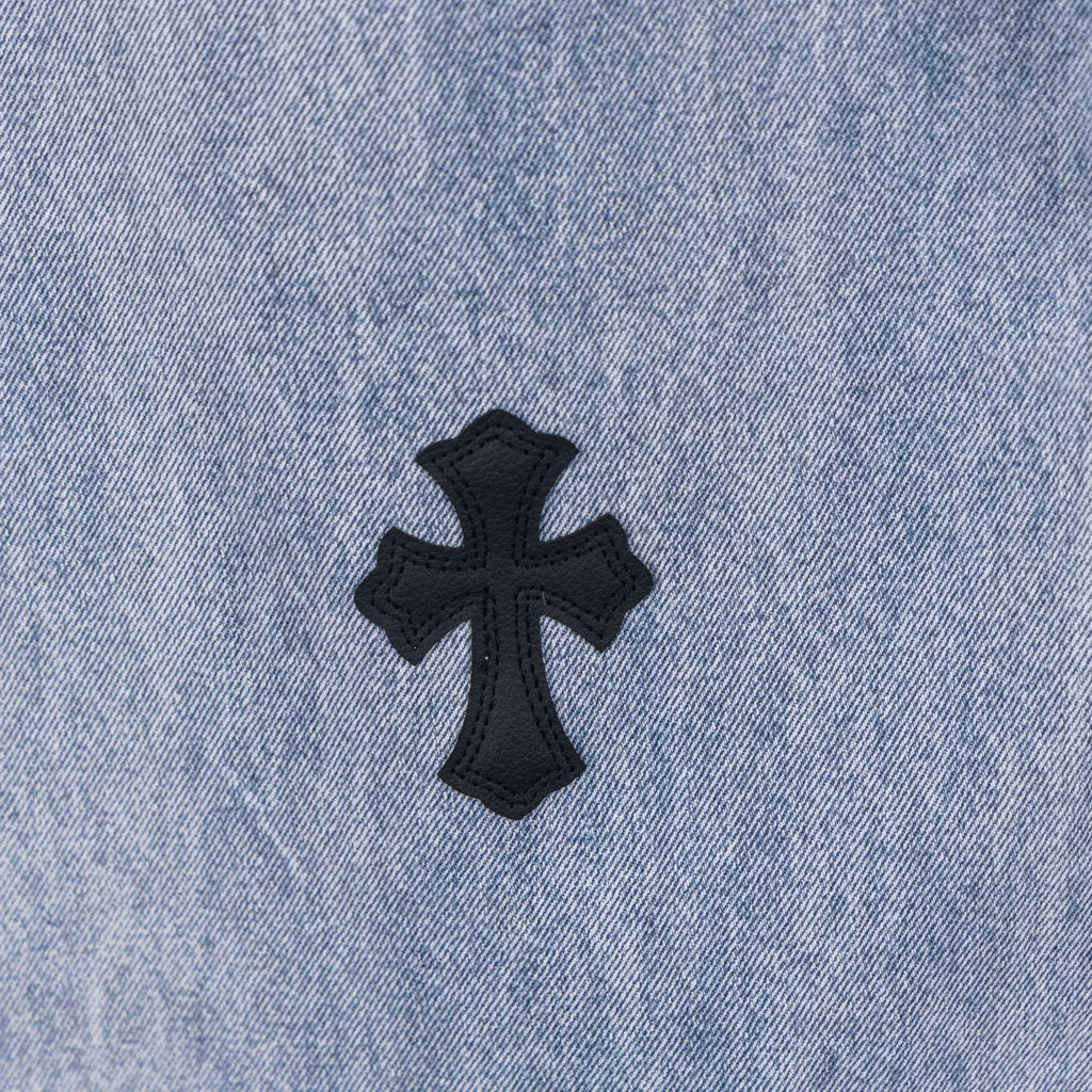 Light wash denim pants with black cross patch applique on fabric