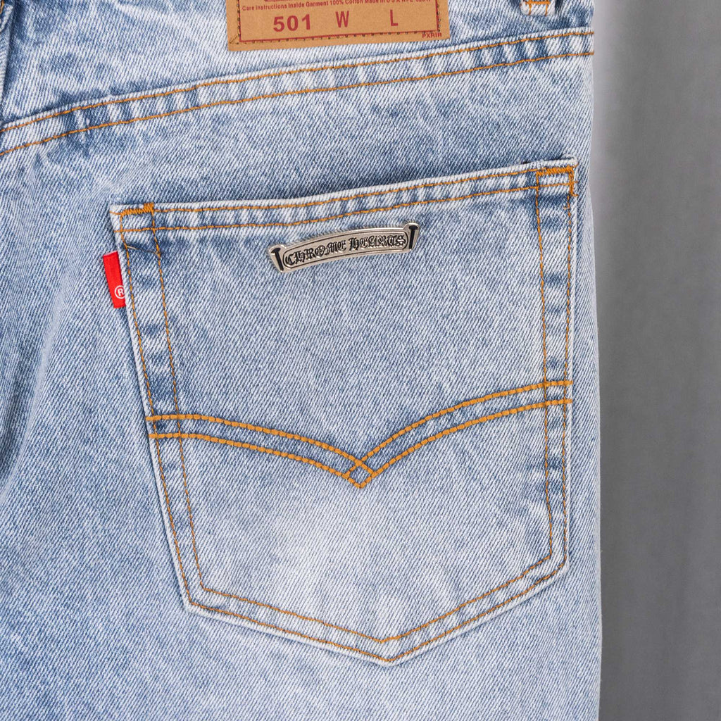 Light blue denim pants back pocket with stitched seams and metal logo patch