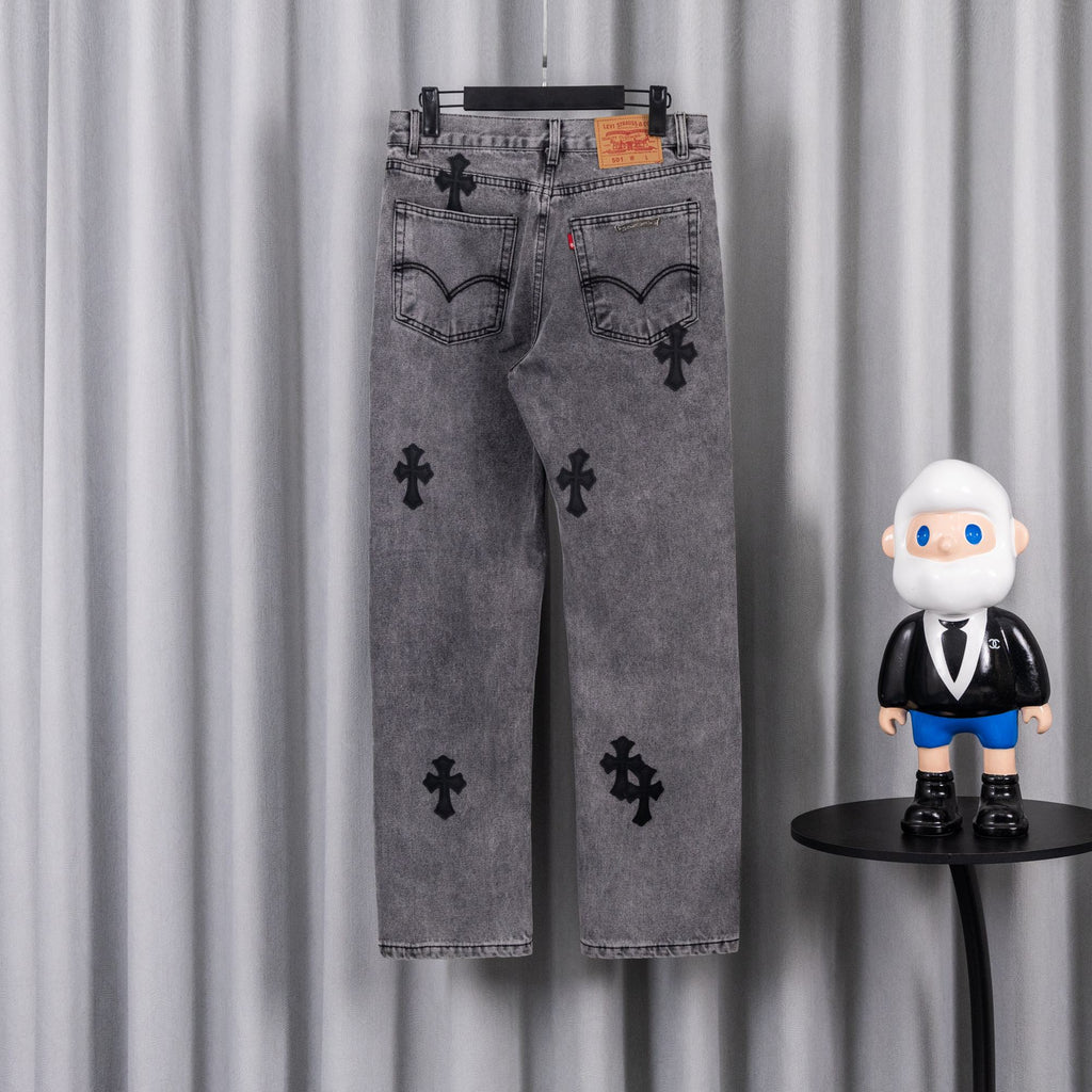 Gray denim pants with black cross applique print, front view on hanger