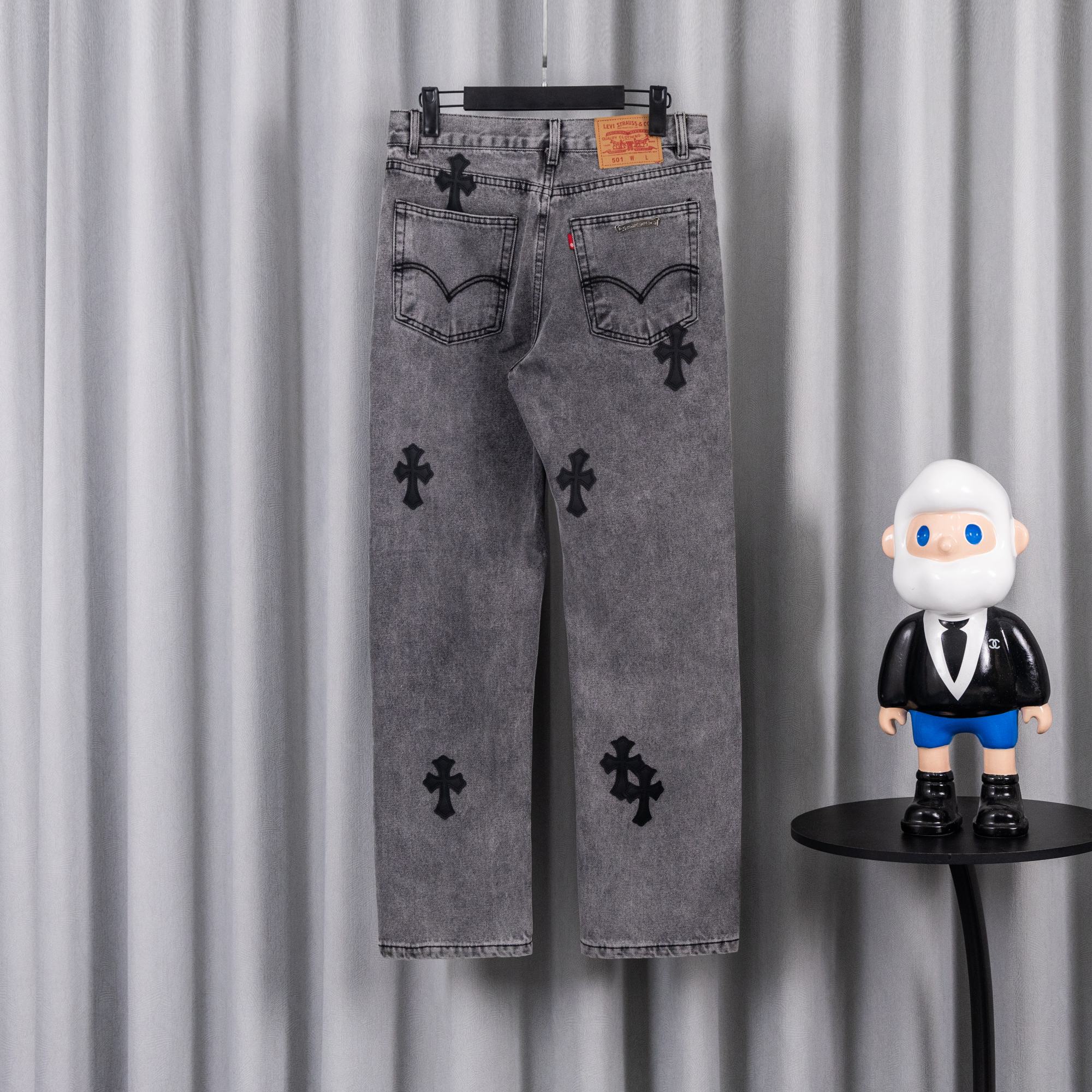 Gray denim pants with black cross applique print, front view on hanger