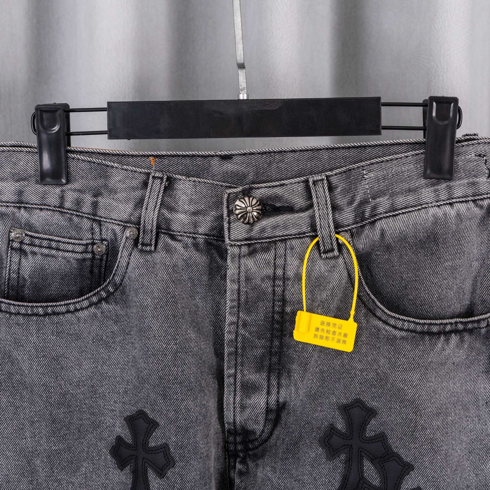 Gray denim pants waistband close-up with metal button, belt loops, and yellow tag
