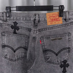 Gray denim pants detail: waistband label, button fly, and cross appliques on pockets
