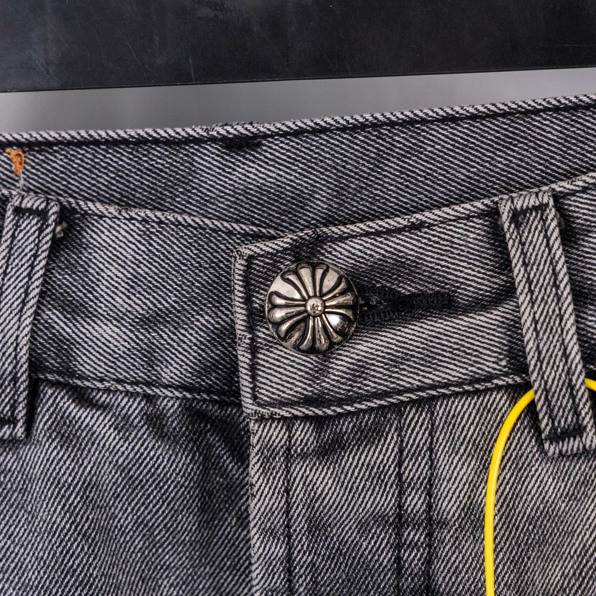 Gray denim pants close-up of waistband button and stitched pocket top