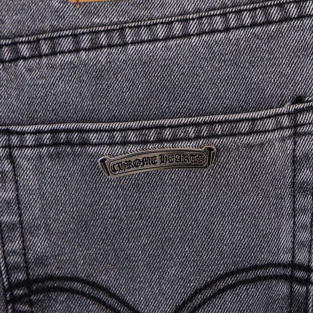 Gray denim pants close-up of back pocket with stitched cross applique