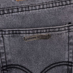 Gray denim pants close-up of back pocket with stitched cross applique