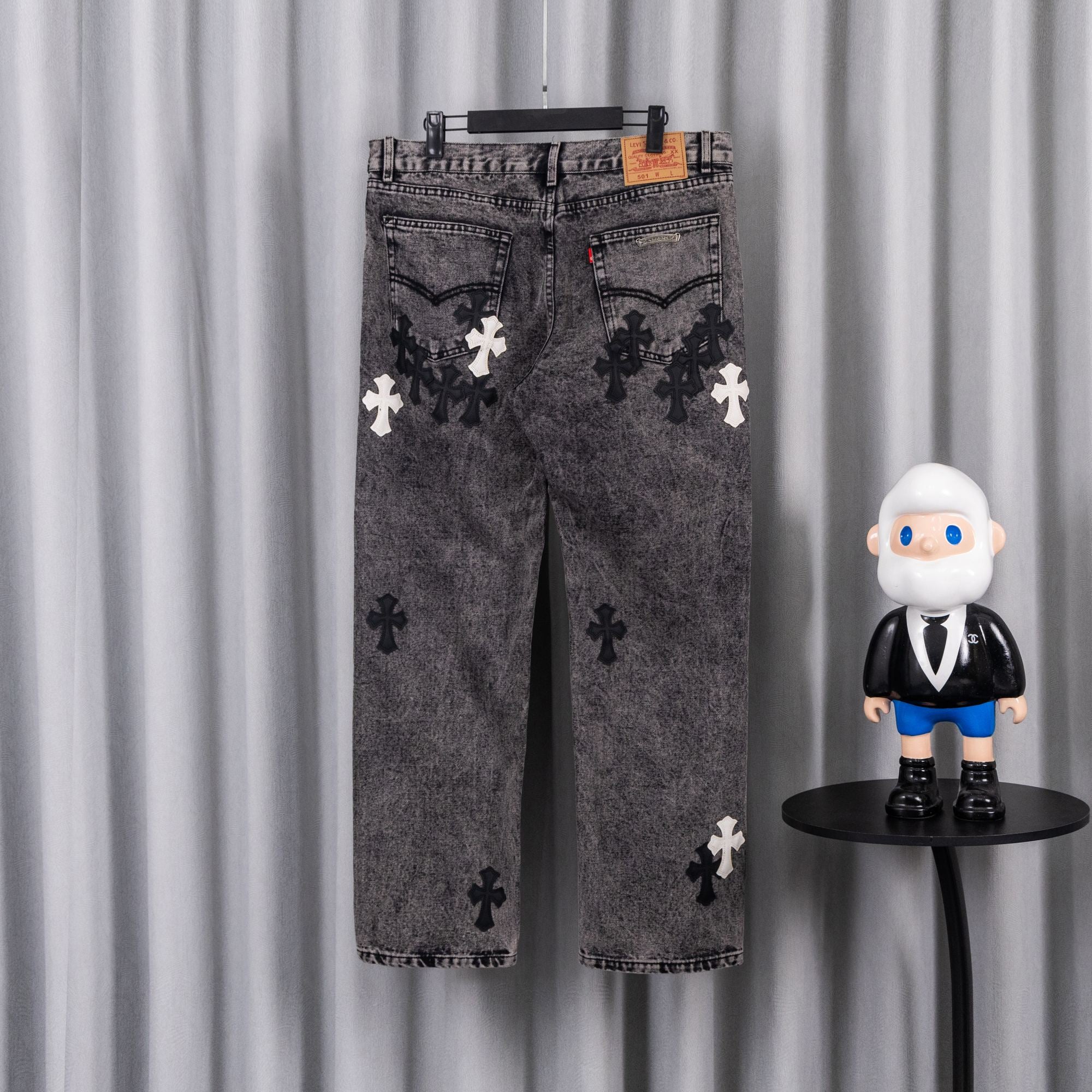 Gray denim pants with dark and white cross patches, belt loops at waistband.