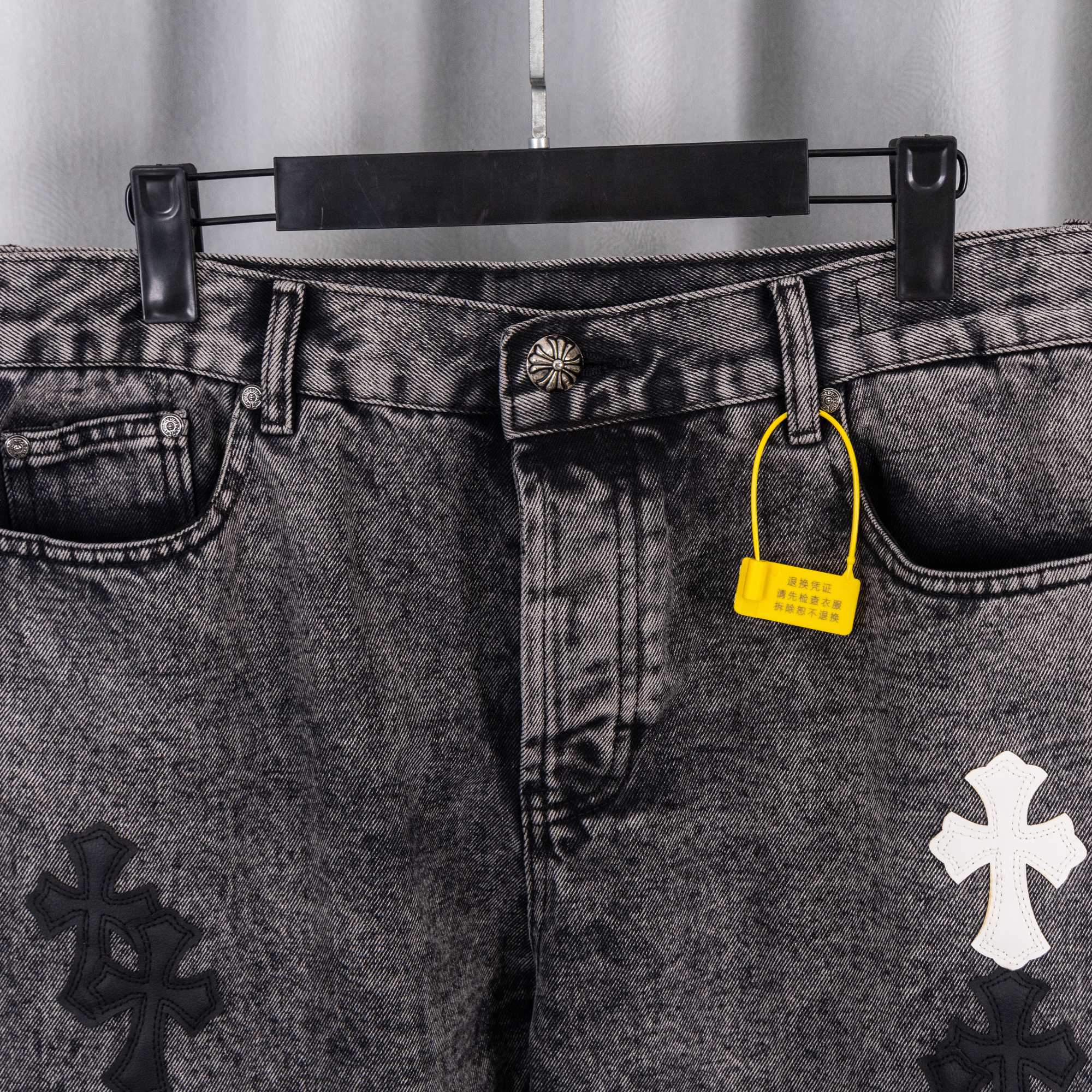 Denim pants waist with button, belt loops, and yellow hang tag near coin pocket.