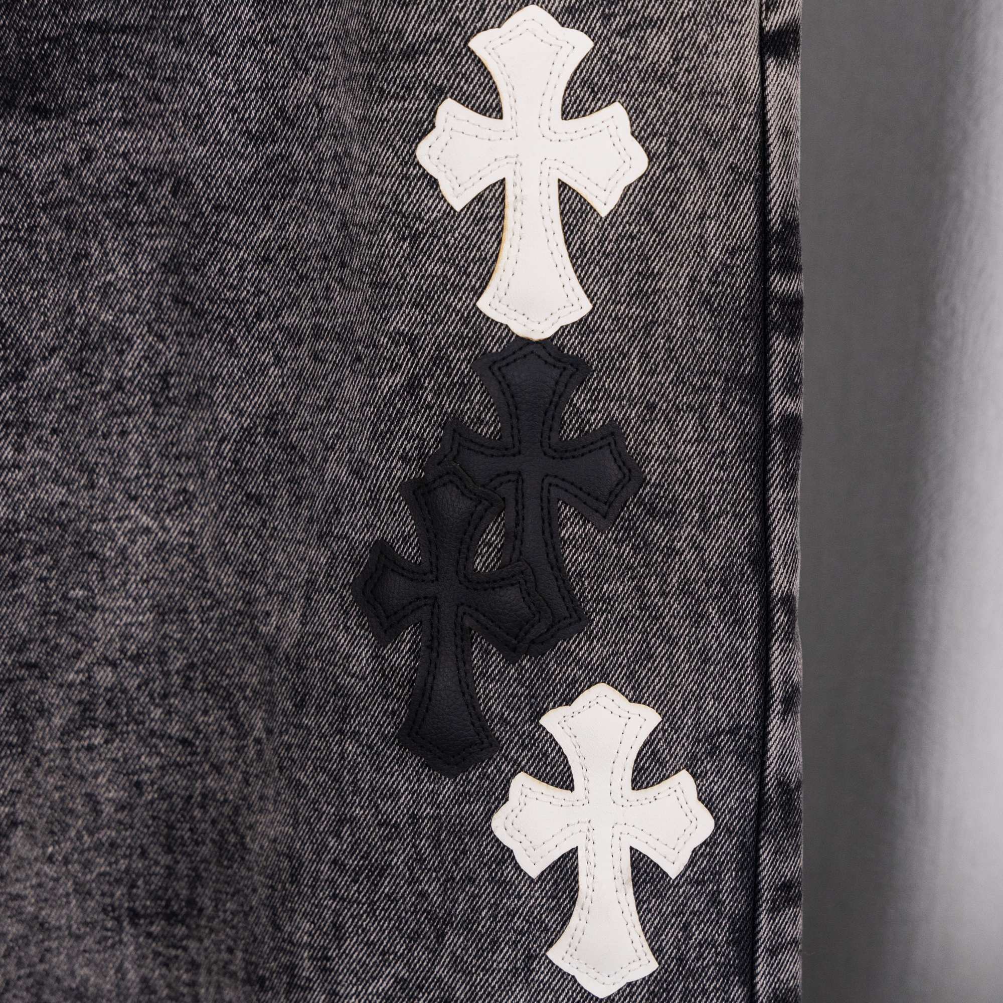 Denim fabric with stacked cross appliques in white and black on front panel.