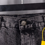 Denim pants waistband button area with metal tab and yellow tag string.