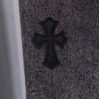 Black cross appliqué on gray denim pants front.