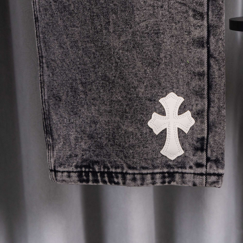 Gray denim pants cuff with a white cross patch.