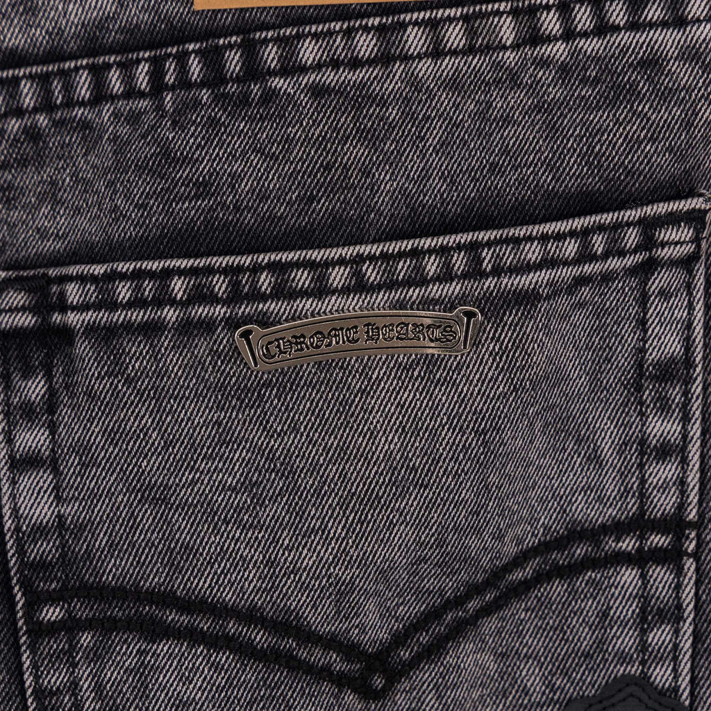 Denim pants back pocket with small metal brand patch.