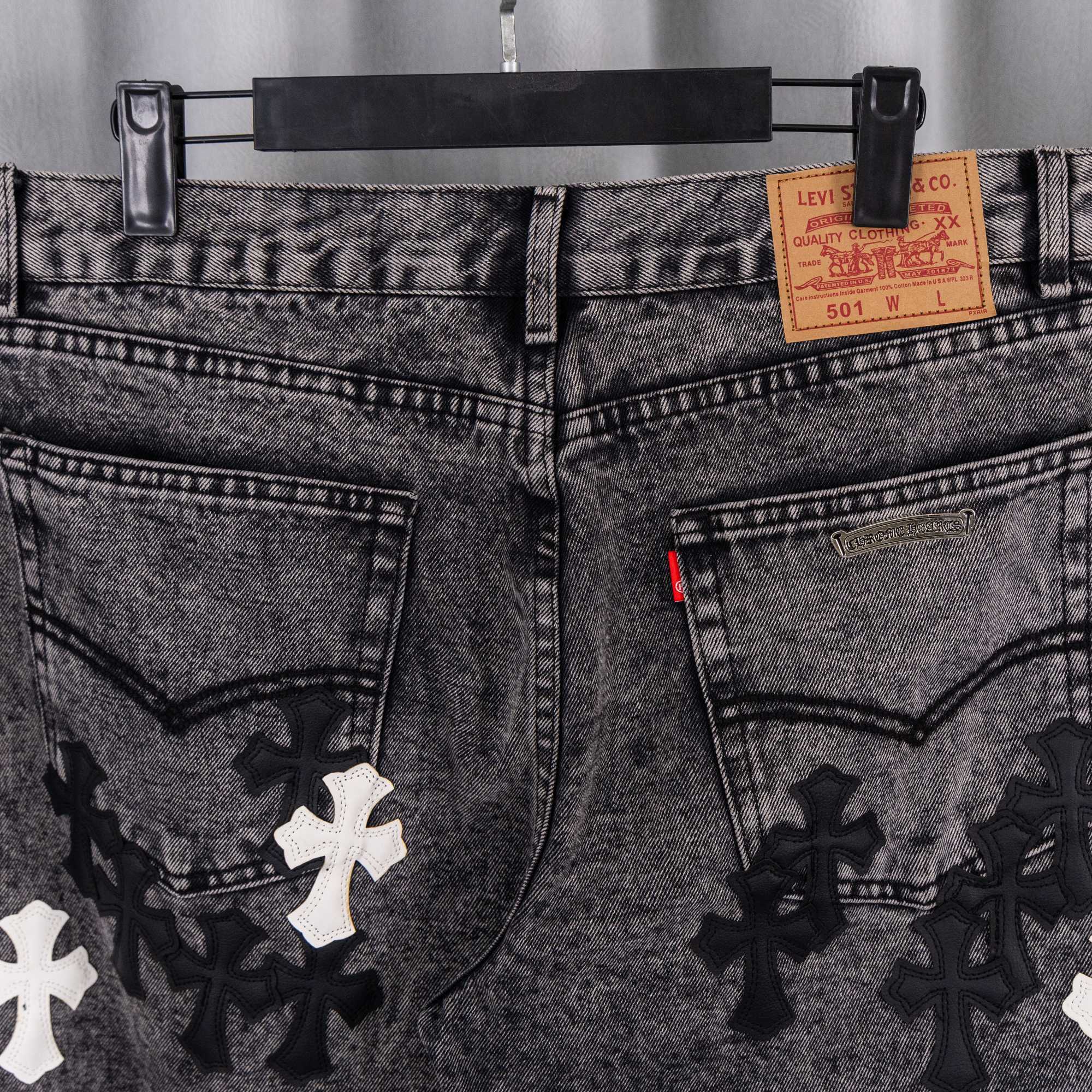 Denim pants front with Levi's label, belt loops, and black/white cross patches.